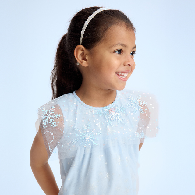 A person is wearing a white hoodie with a teddy bear graphic surrounded by stars and a heart. Paired with black pants featuring heart and stripe designs. Casual outfit suitable for everyday wear or lounging. Image emphasizes clothing details and design features. banner