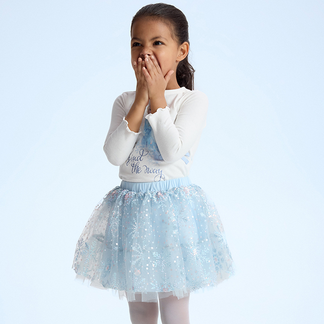 A child wearing a white long-sleeve top with text 